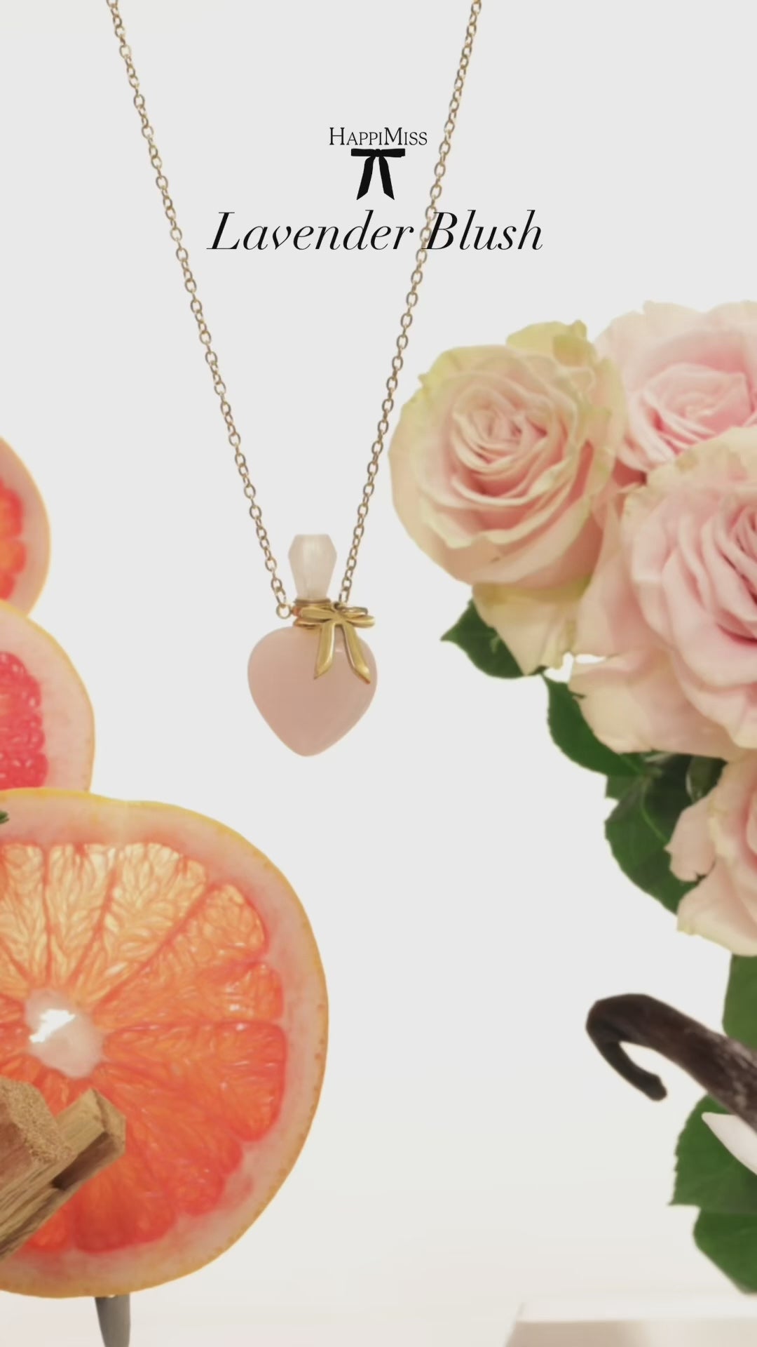 Load video: Beautiful fresh pink roses with a lovely light lavender bundle flank each side of the video.  With sandalwood sticks, vanilla beans, and orchids nestled in.  The center of the video shows the star, our rose quartz heart perfume. Necklace.  Filled with our signature scent, HappiMiss Lavender Blush.